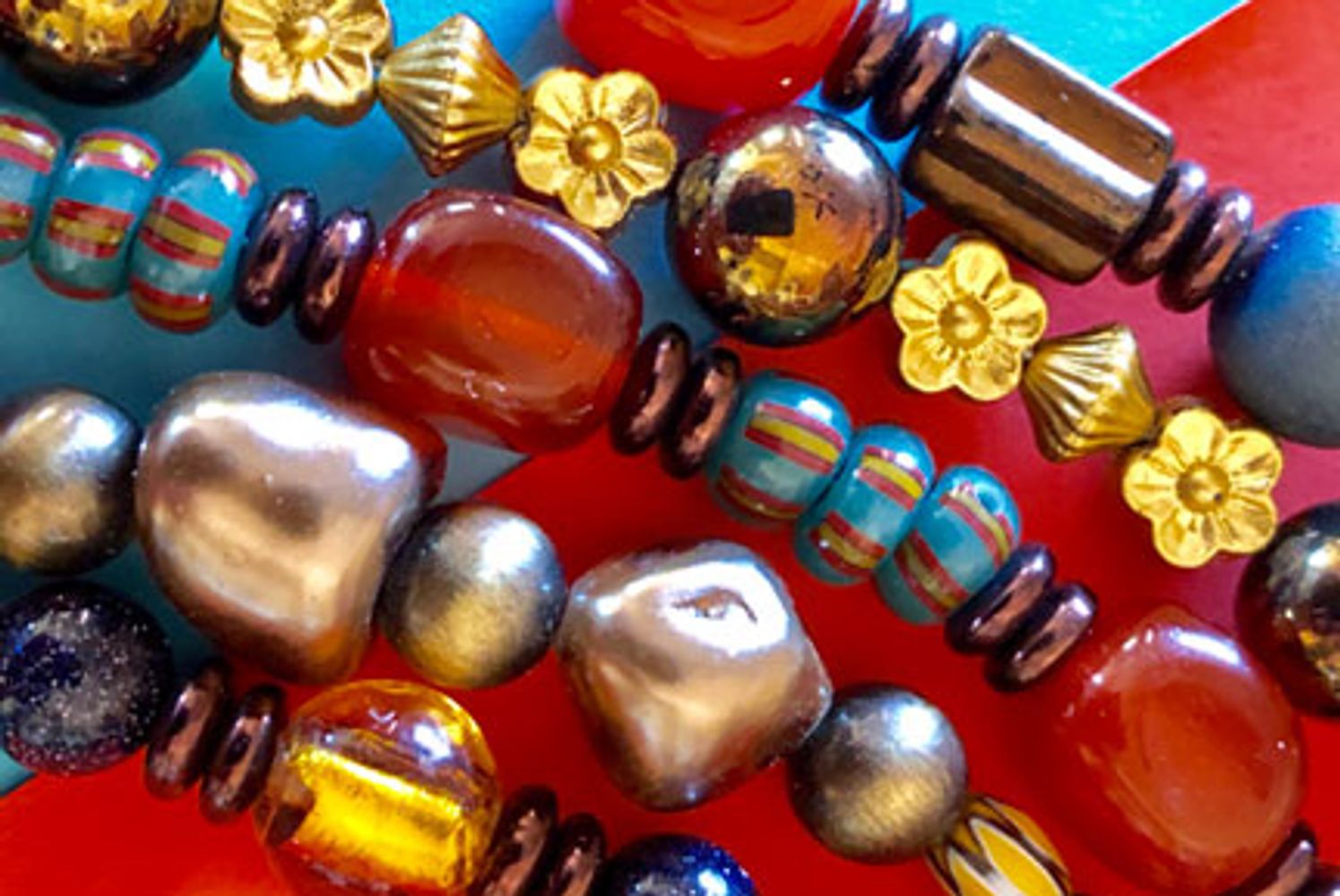 Colorful beaded necklaces with bird-shaped pendants on a black background.