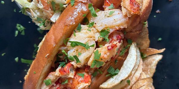 lobster roll, warm lobster roll with warm butter on a plate with potato chips, coleslaw