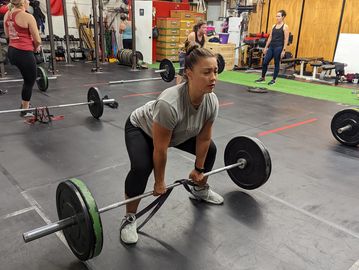 A woman is set up with a barbell preparing for a deadlift
