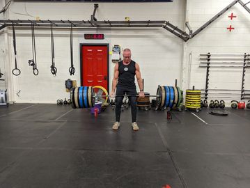 A muscular man is holding a heavy barbell and standing it up in a deadlift