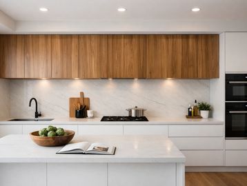 Modern kitchen with wood cabinets and marble countertops.