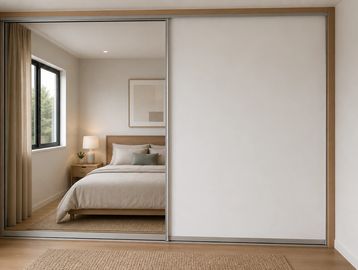 Minimalist bedroom with a mirrored sliding closet door and neutral tones.