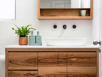 Modern bathroom vanity with wooden cabinets and a white vessel sink.