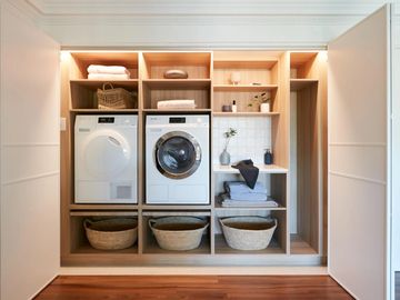 Organized laundry nook with washer, dryer, baskets, and shelves.