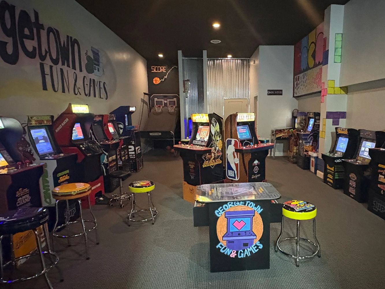 Retro arcade gaming room with classic game machines and stools.