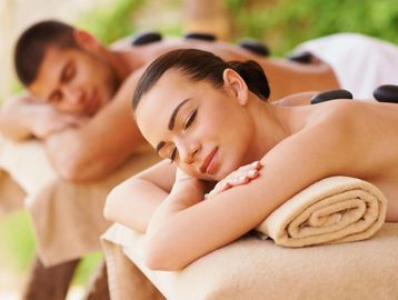 Couple enjoying a hot stone massage at a spa.