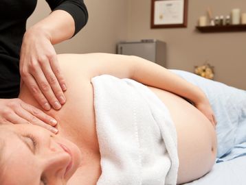Pregnant woman receiving a shoulder massage.