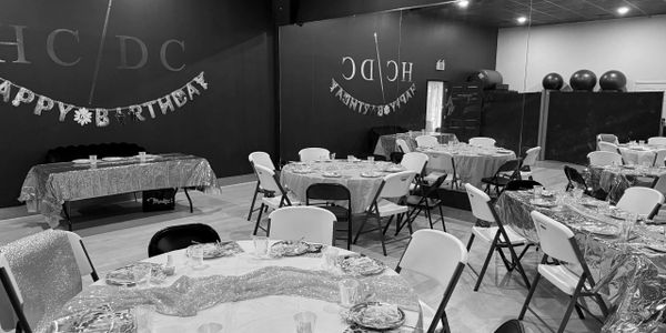 Decorated room with tables and chairs set for a birthday party.
