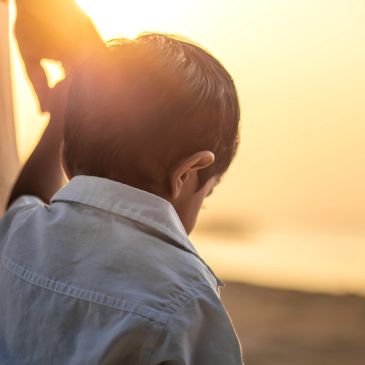 Young boy in a white shirt gazing at a sunset.