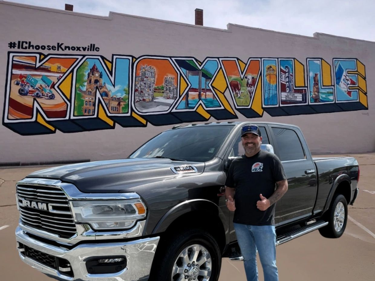 A man standing in front of a truck with graffiti on the side.