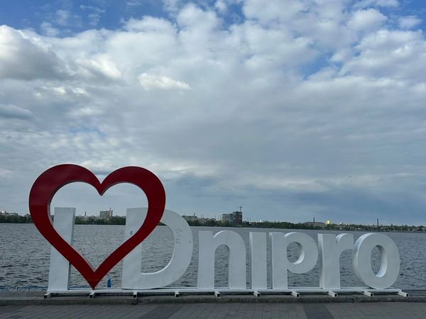 Large 'I love Dnipro' sign by the water under a cloudy sky.