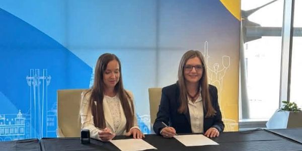 Two women signing documents at a table.