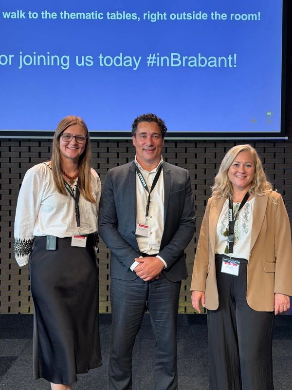 Three professionals posing at a conference in Brabant.