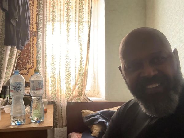 Man with beard smiling in dim room.