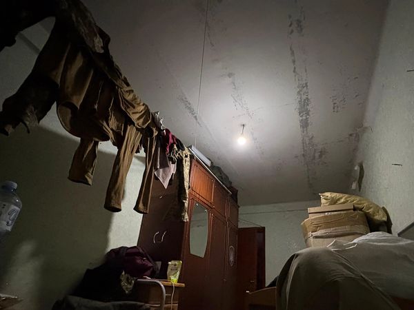 Dimly lit room with hanging clothes and furniture.