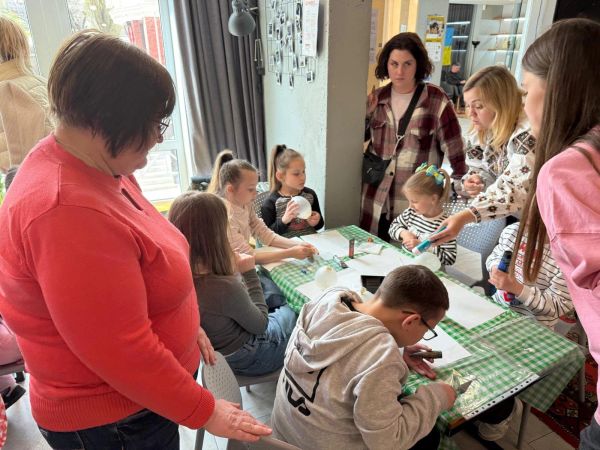 Adults and children engaged in a creative group activity.