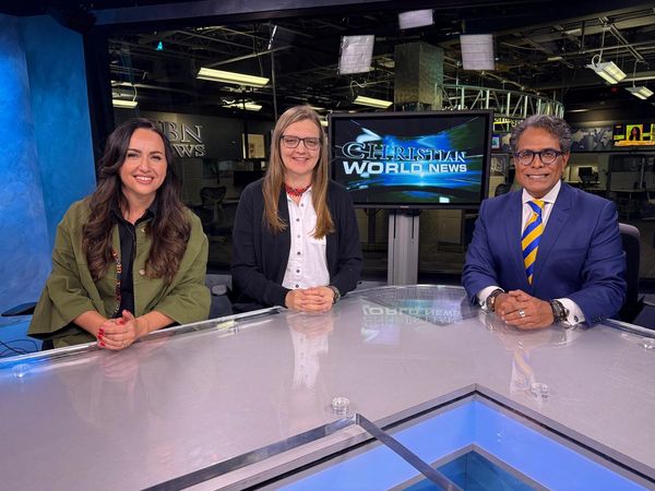 Three news anchors sit at a news desk with a 'Christian World News' screen behind them.