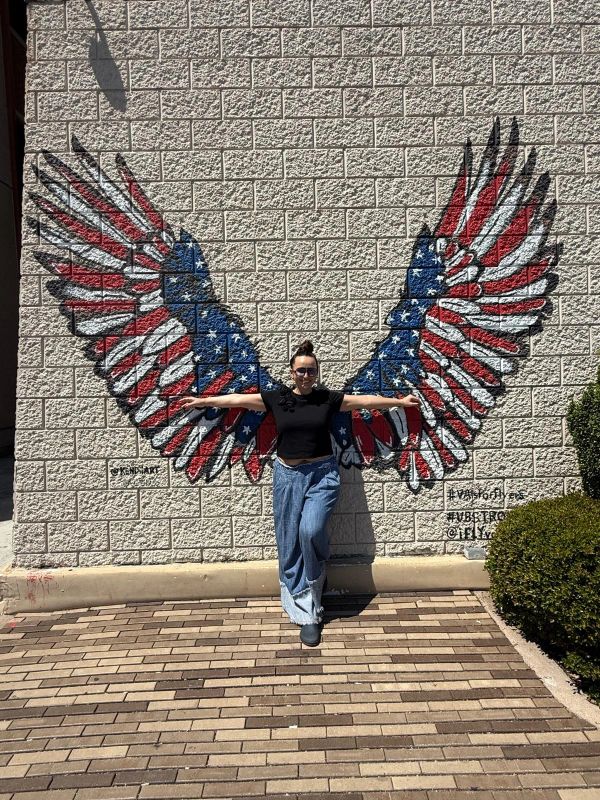 Person poses with American flag wings mural.