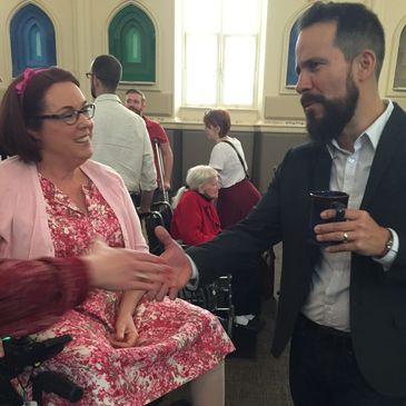 woman on wheelchair smiling at man who is extending his hand to someone out of the frame