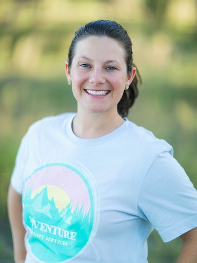 A smiling pediatric occupational therapist ready to help among a blurred nature background.