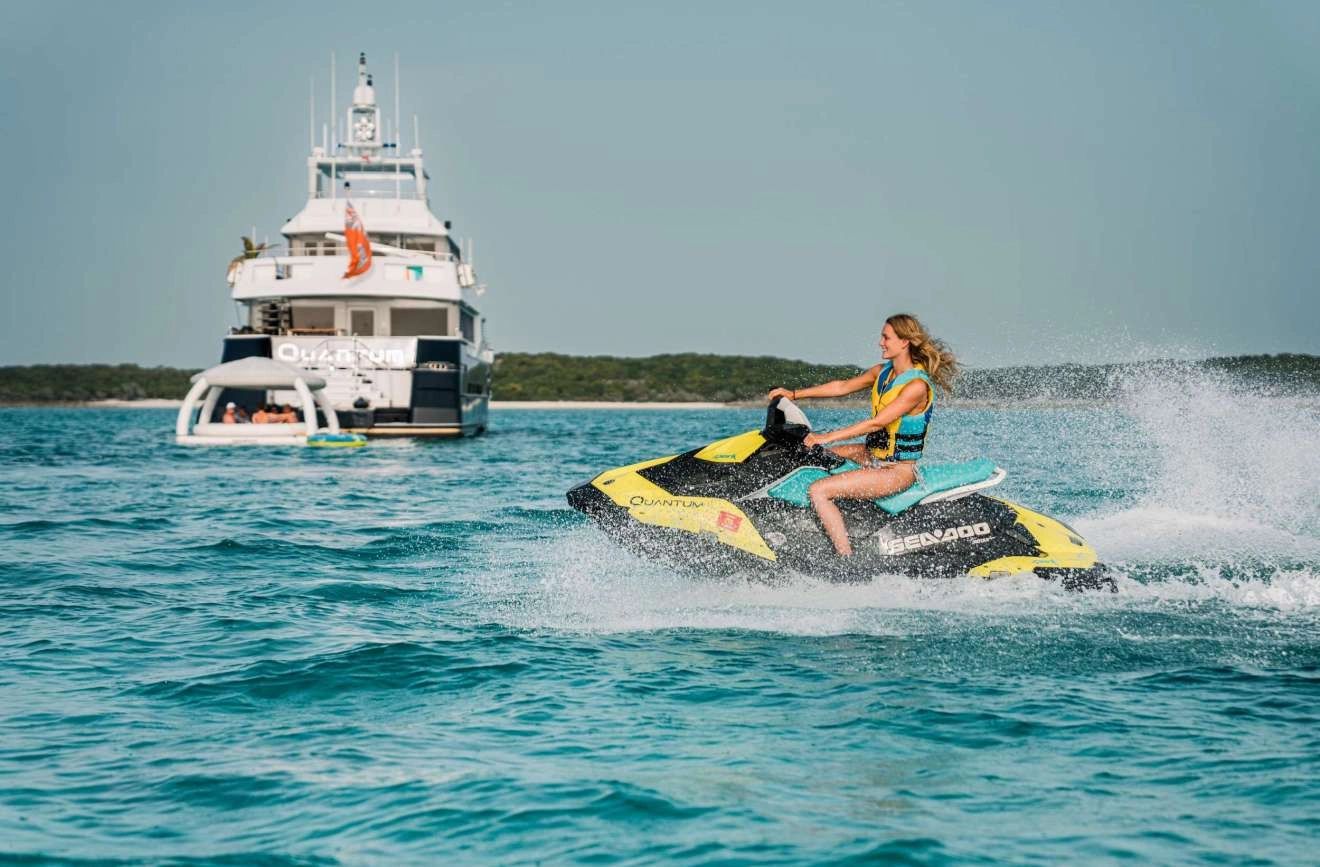 quantum 125 foot yacht anchored in the bahamas and guests enjoying jetski activity