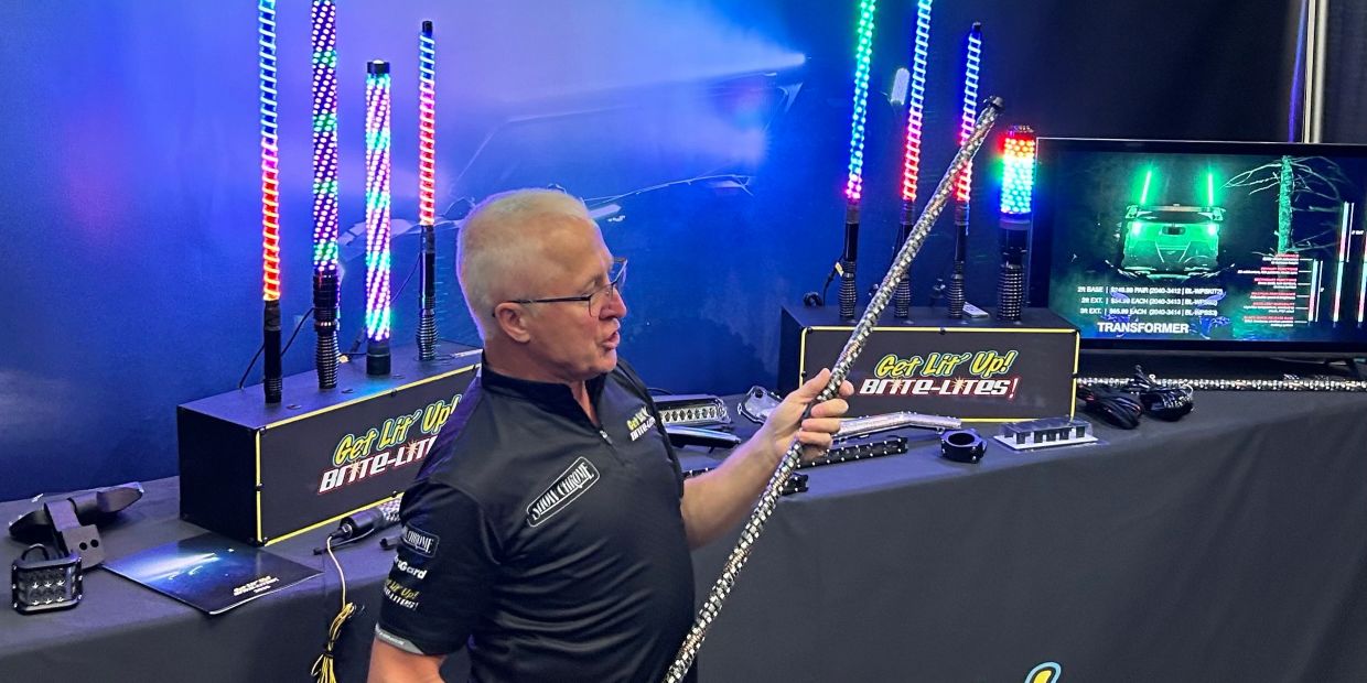 Man showcasing LED light sticks at a booth.