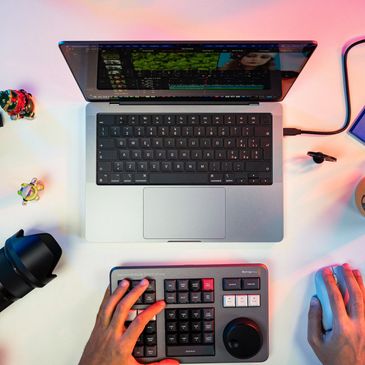 person editing video footage on a laptop with several other items sitting around the table