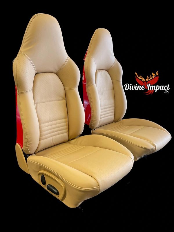 A pair of beige leather seats with red trim
