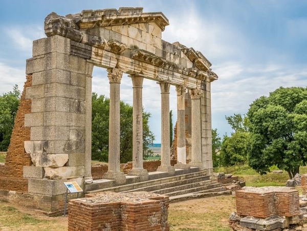 Ancient Roman ruins with stone columns and steps surrounded by greenery.