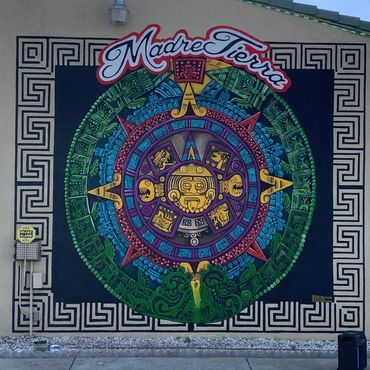 Large-scale Aztec calendar mural painted outside a restaurant.