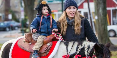 Christmas tree lighting pony rides with pony with ribbons in hair. 