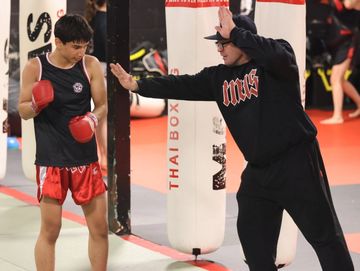 Coach training young boxer in a Thai boxing gym.