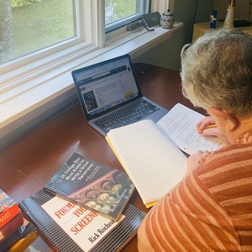 Rick Reichman editing a screenplay at a desk in front of a window