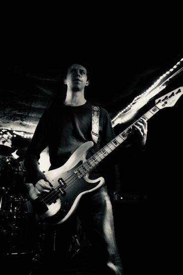 Black and white photo of a man playing electric bass guitar.