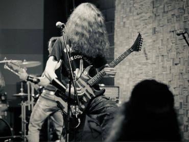 Long-haired guitarist performing on stage.