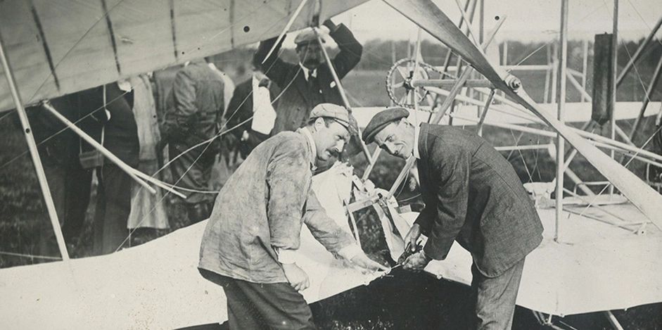 Two men working on an early airplane.