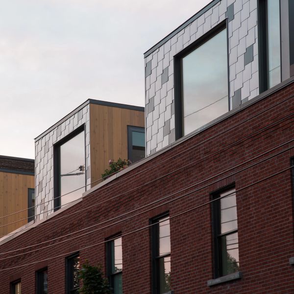 Modern rooftop extensions with large windows atop a brick building at sunset.