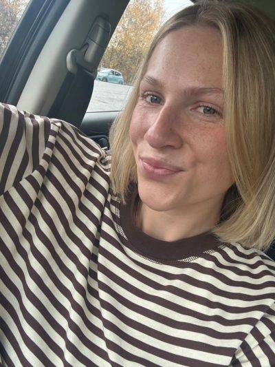Young woman in striped shirt taking a selfie in a car.