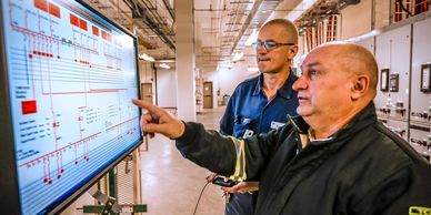 two electricians reviewing computer in industrial building