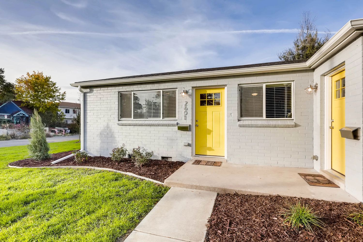 photo of a grey house with a yellow door.