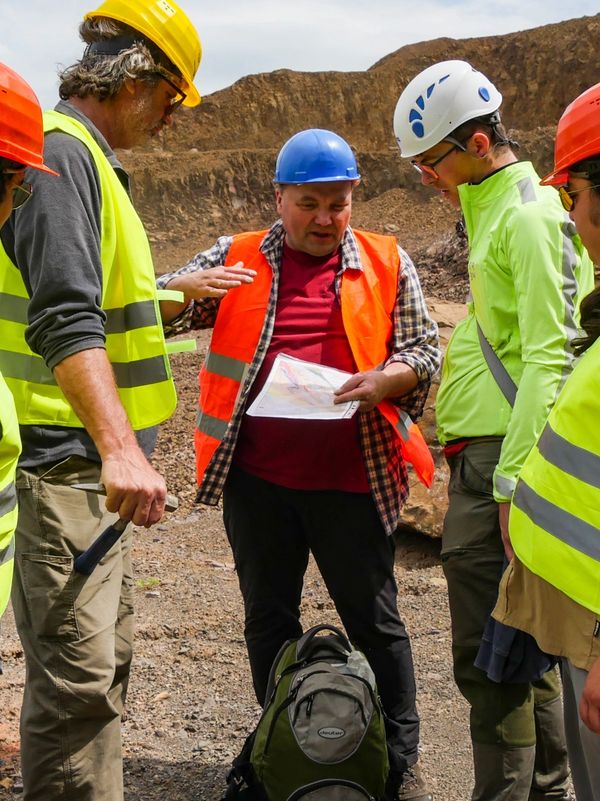Group of construction workers discussing plans at a rocky site.