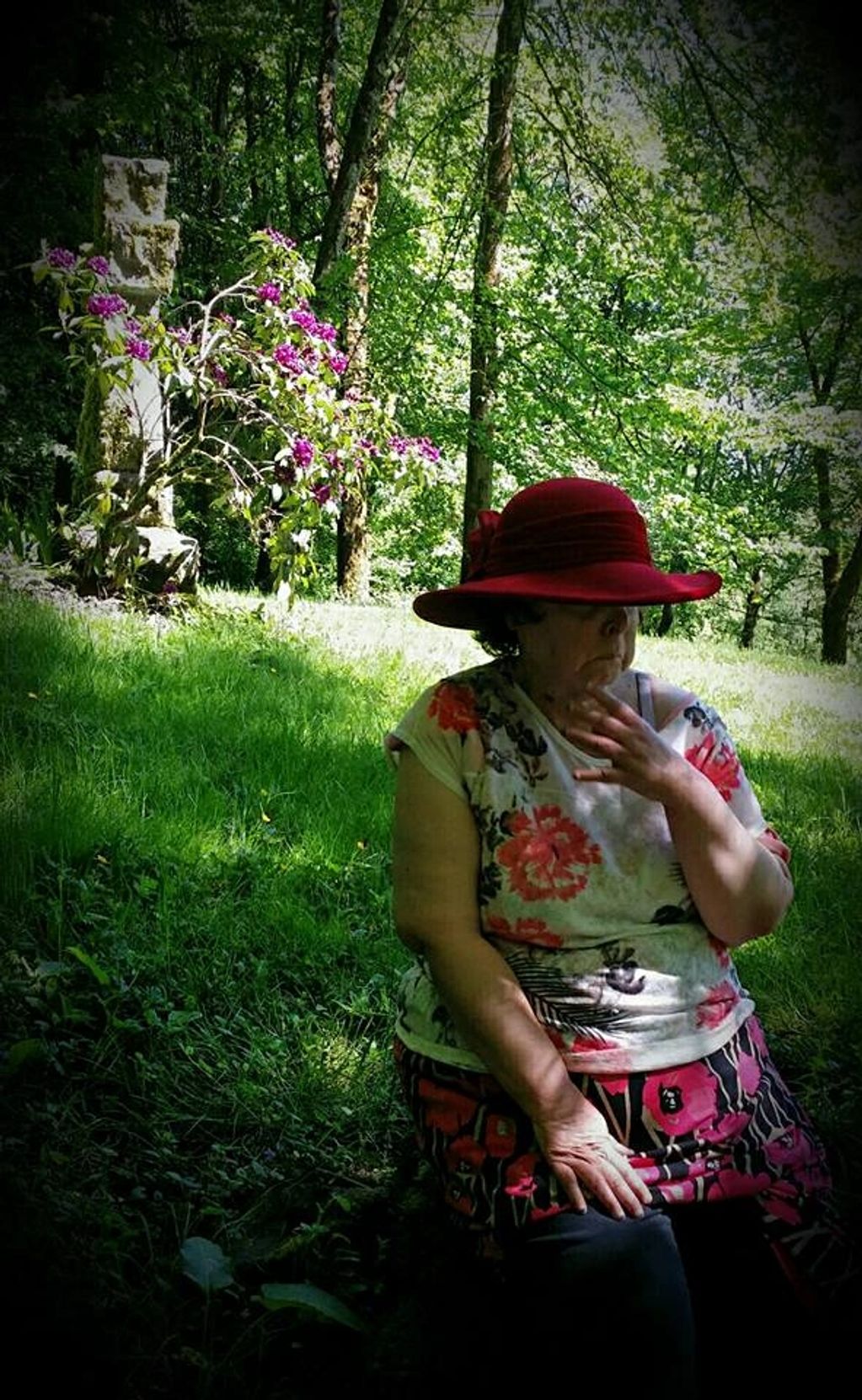 Sad looking woman wearing a red hat in a beautiful cemetery. 