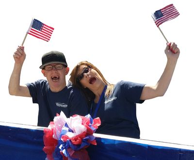 An excited man and woman waving small American flags.