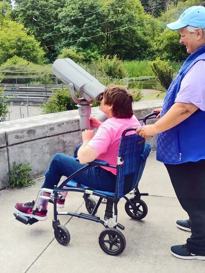 Support woman with a woman in a wheelchair looking through a telescope.