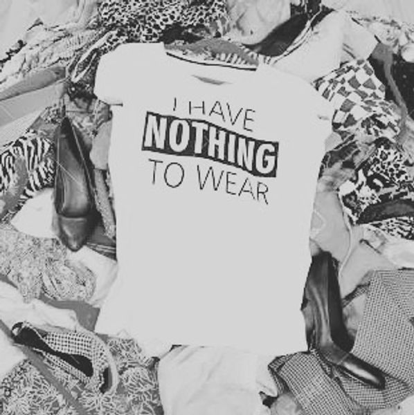 pilha de roupas com camiseta escrito "eu não tenho nada para vestir" em inglês