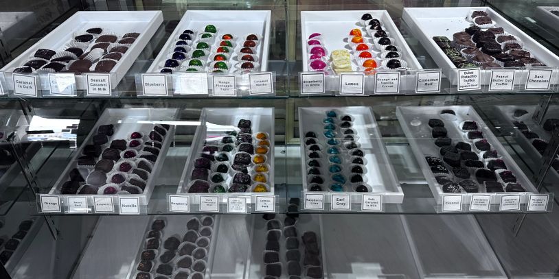 A display of assorted chocolates in a glass case with various flavors labeled.