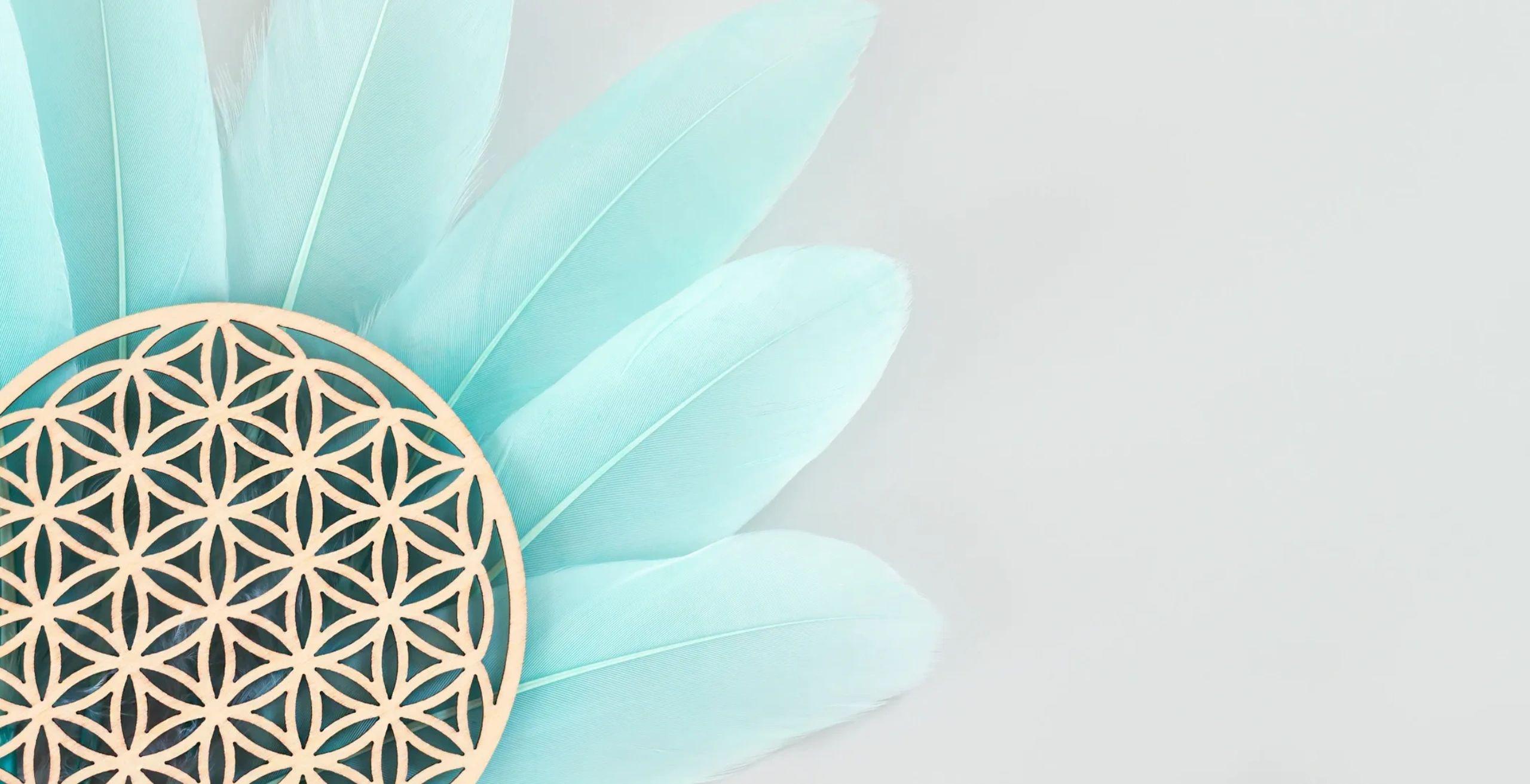 Intricate wooden mandala on soft blue feathers against a light background.