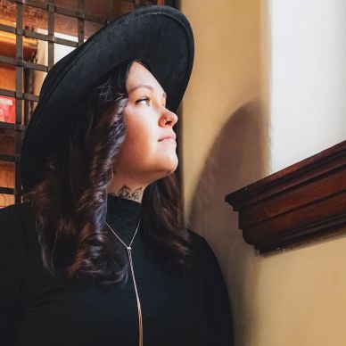 Woman in black hat gazing thoughtfully out window.