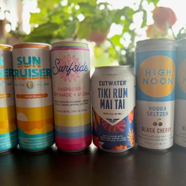 A lineup of six colorful canned beverages with various flavors and brands.