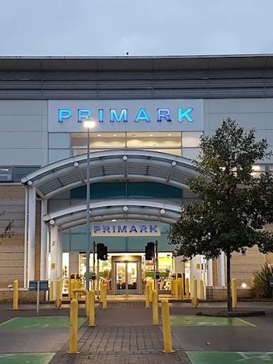 Primark store entrance with illuminated signage at dusk.